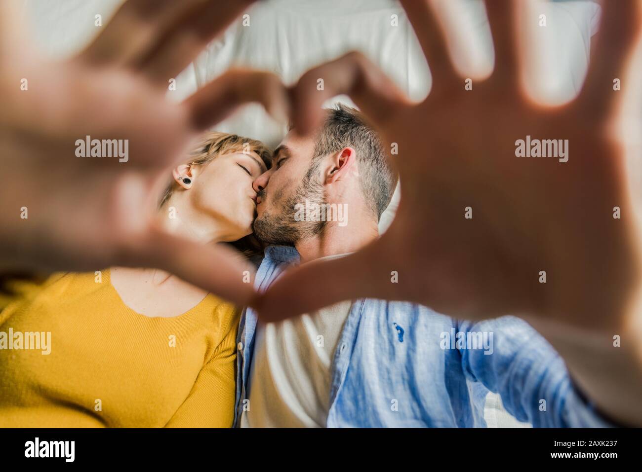 Giovane coppia romantica in una data, baciare attraverso un gesto del cuore fatto con le dita. Due bellissime coppie innamorate che trascorrono del tempo insieme sulla b Foto Stock