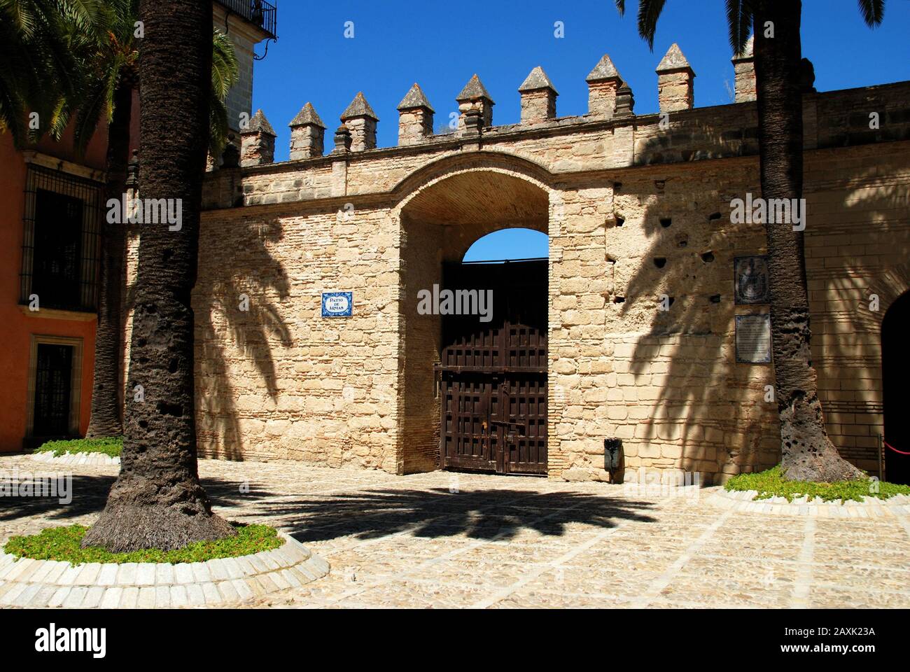 Muro con merli e grande porta nel cortile del castello (patio de Armas), Jerez de la Frontera, Cadice provincia, Andalusia, Spagna. Foto Stock