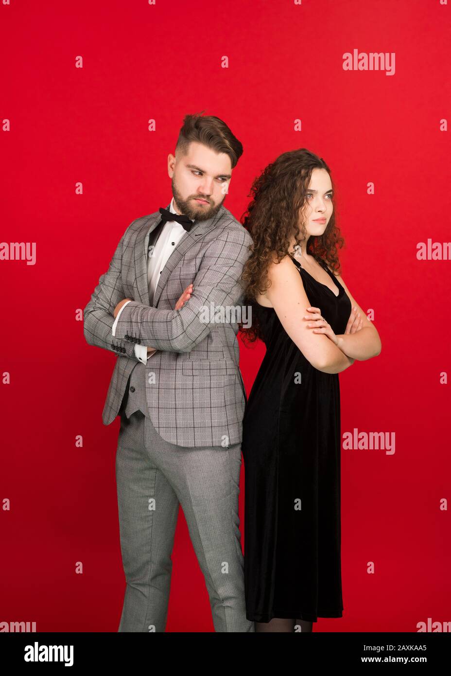 L'uomo e la donna irritati che si alzano indietro con le braccia ripiegate isolate su sfondo rosso. Foto Stock L'uomo e la donna irritati che si alzano indietro con le braccia ripiegate isolate su sfondo rosso. Foto Stock