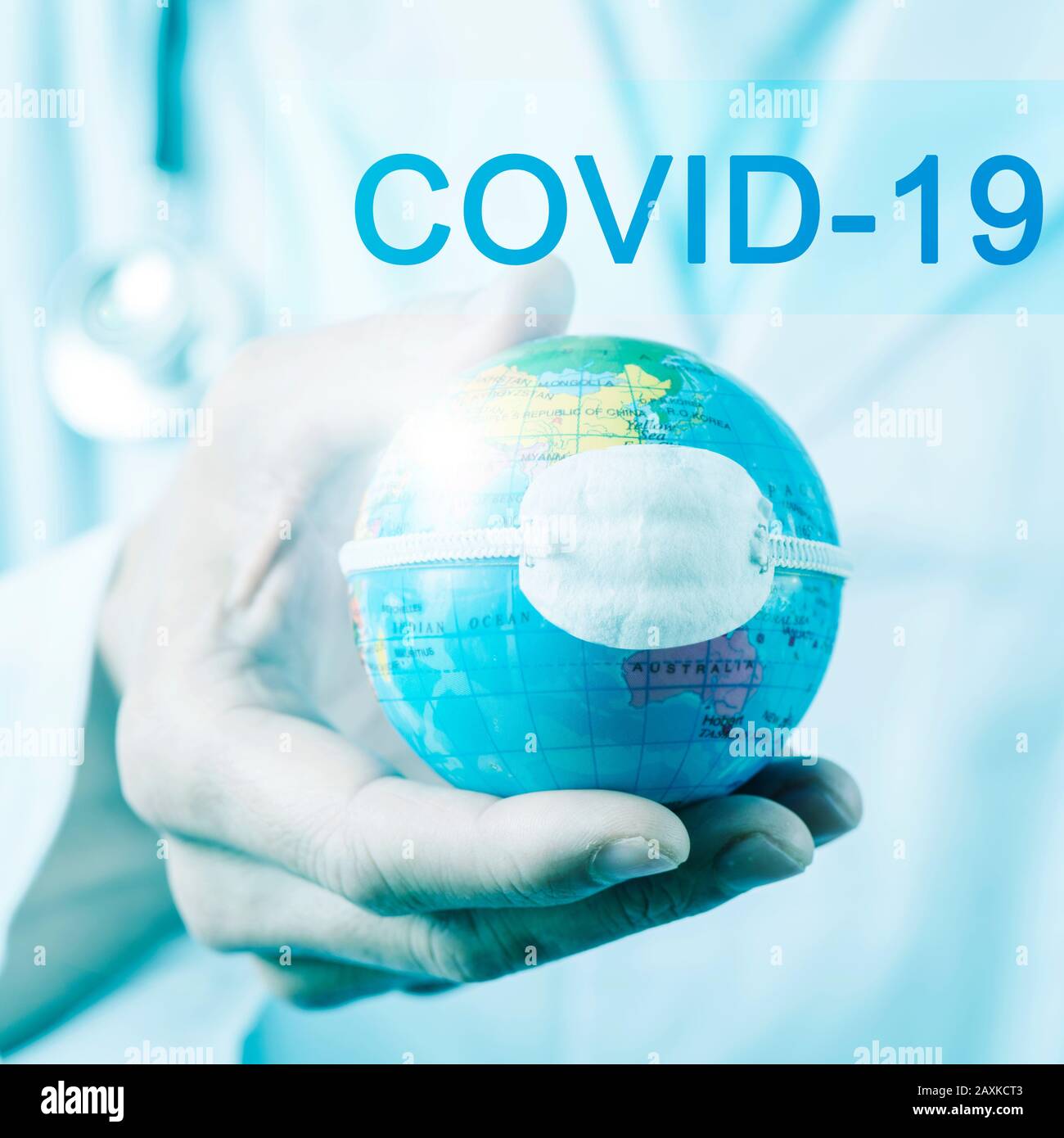 closeup di un medico caucasico uomo che detiene un mondo con una maschera protettiva e il testo covid-19, per la malattia di coronavirus 2019 Foto Stock