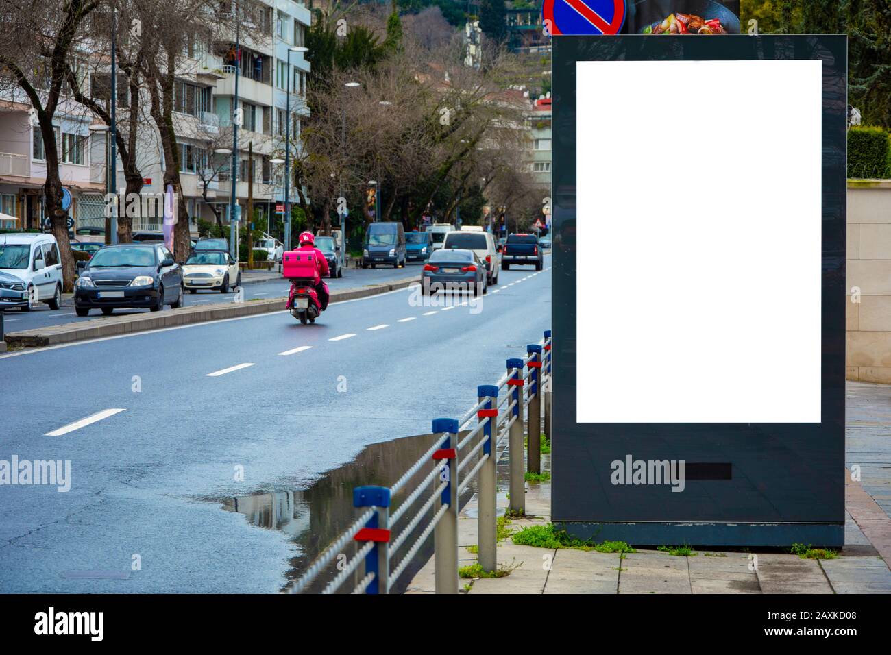 Grande billboard vuoto sul marciapiede su una strada affollata con auto che guidano in città Foto Stock