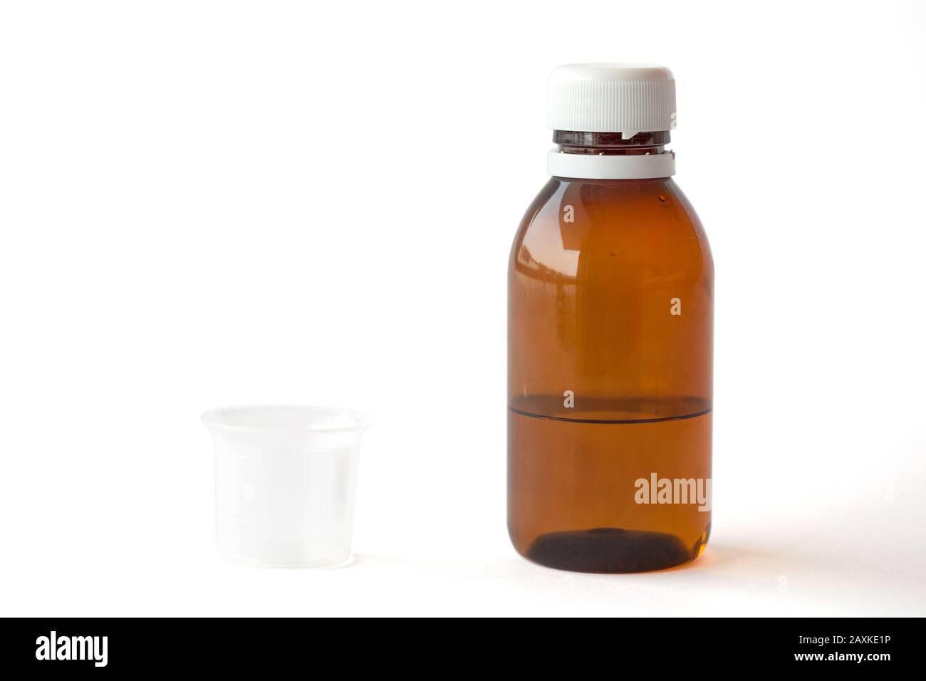 Flacone in plastica trasparente con medicinale liquido e una piccola tazza di misurazione su sfondo bianco con percorsi di lavoro Foto Stock