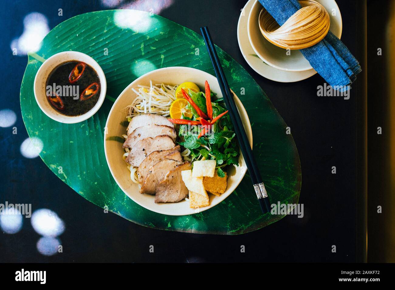 Angolo alto primo piano di ciotola di Cao Lau noodles con carne di maiale alla griglia ed erbe. Foto Stock