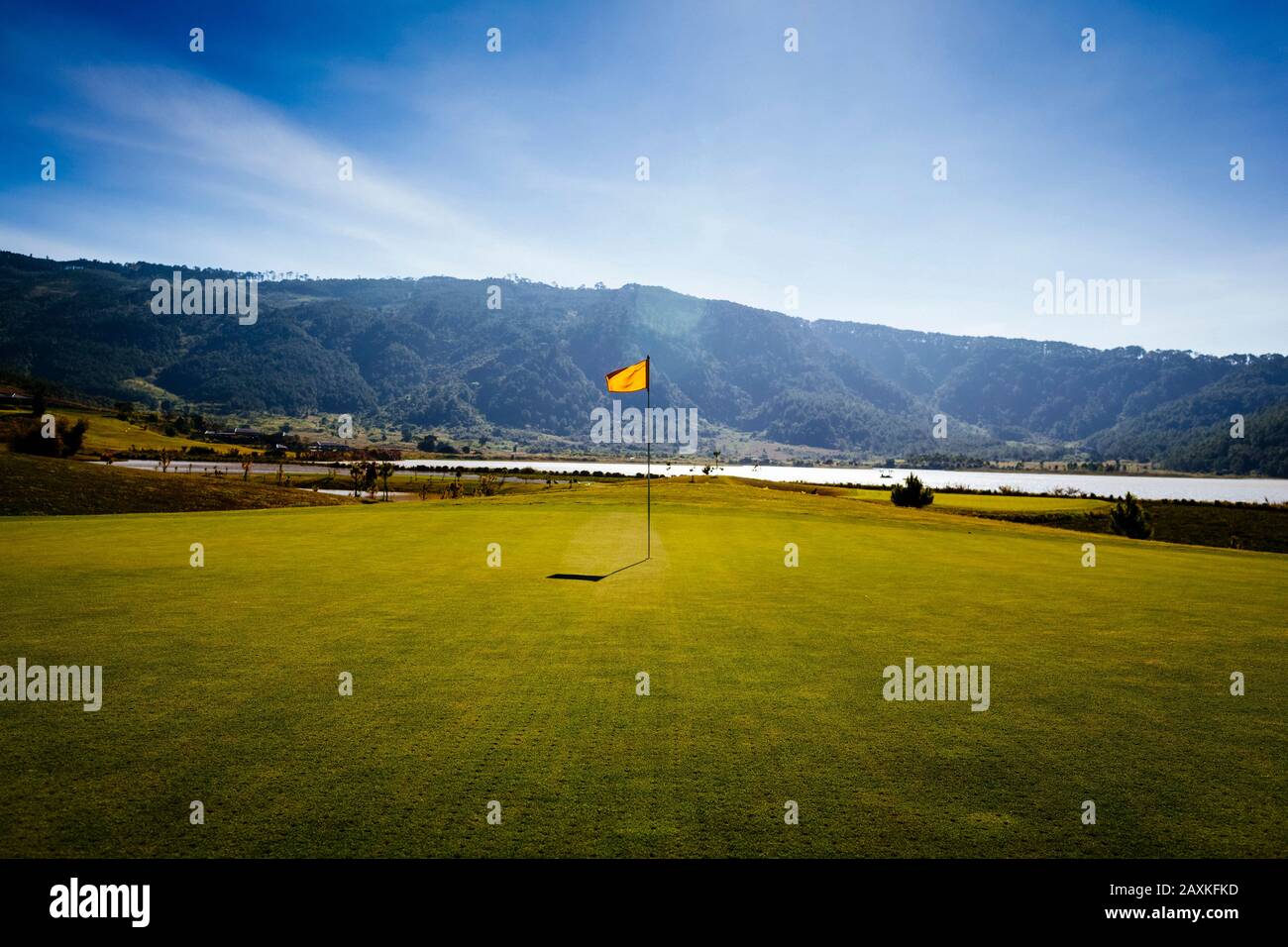 Bandiera su un campo da golf con mare e montagne in lontananza. Foto Stock