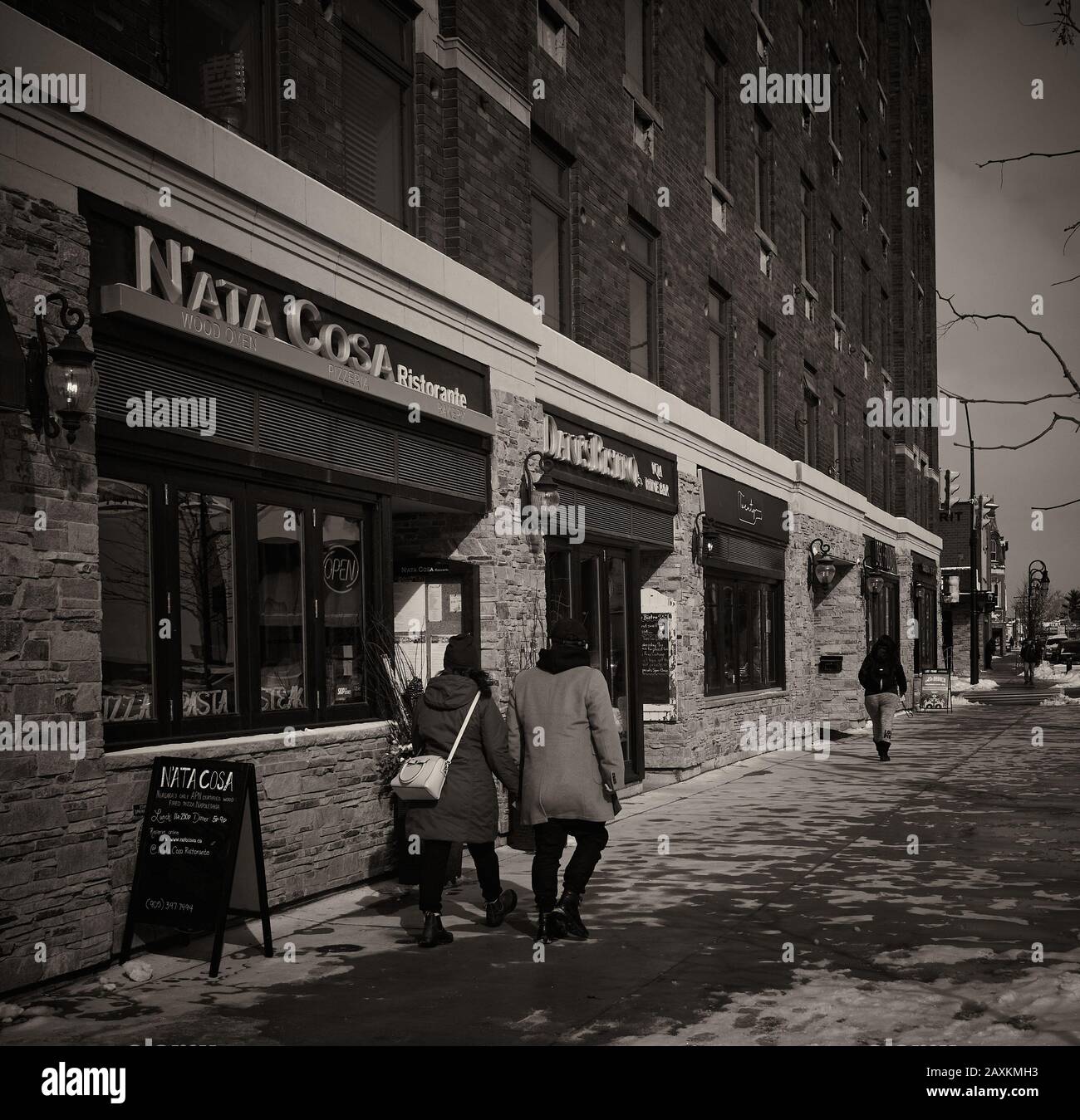 Foto in bianco e nero di coppia passeggiando davanti ad un ristorante italiano in inverno. Foto Stock