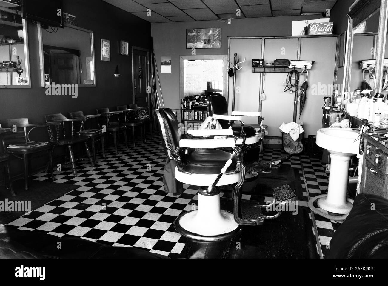 Vintage Barber Shop con pavimenti piastrellati in bianco e nero e sedie girevoli in pelle e lavandini in porcellana. Foto Stock
