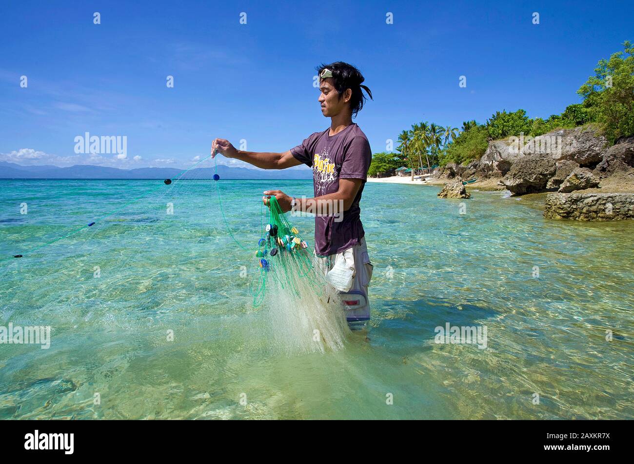 Pesca del pescatore con pesci di esca di fishnet nella laguna, spiaggia bianca, Moalboal, Cebu, Filippine Foto Stock
