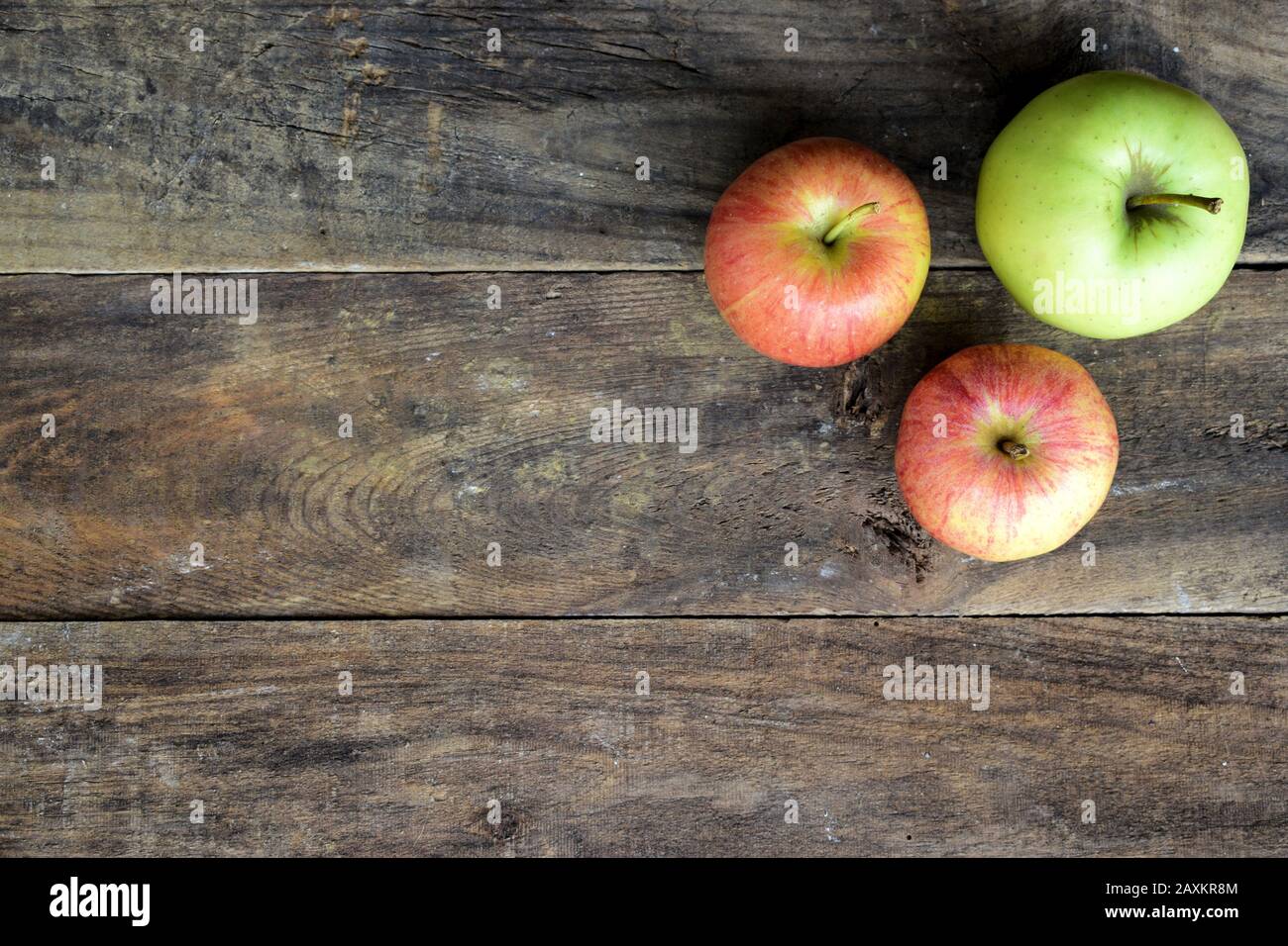 Vista verticale di due mele rosse e verdi sulla parte superiore di un vecchio tavolo in legno Foto Stock