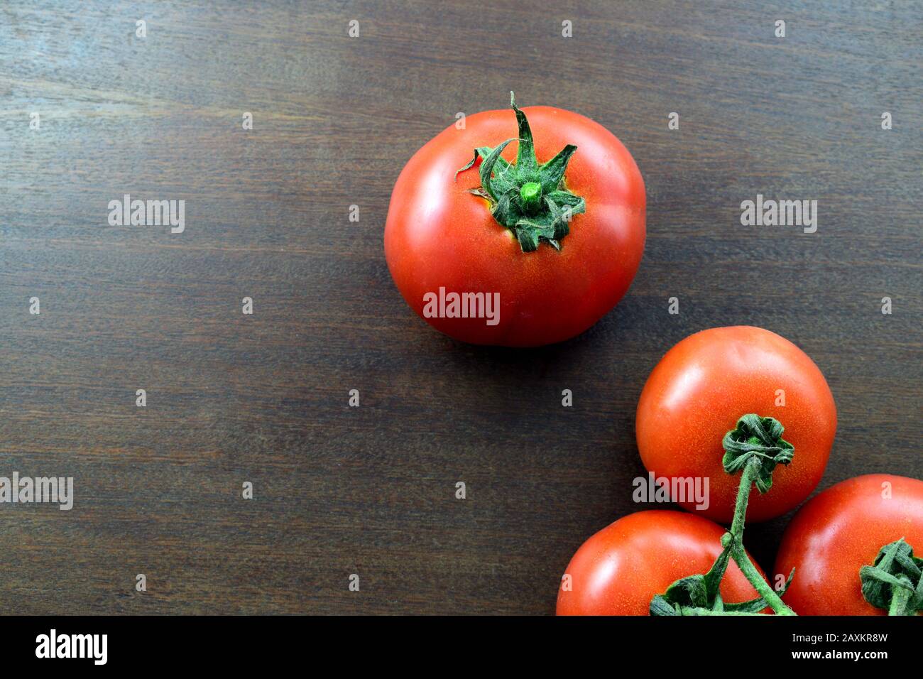 Pomodori rossi luminosi su un tavolo di legno marrone scuro Foto Stock