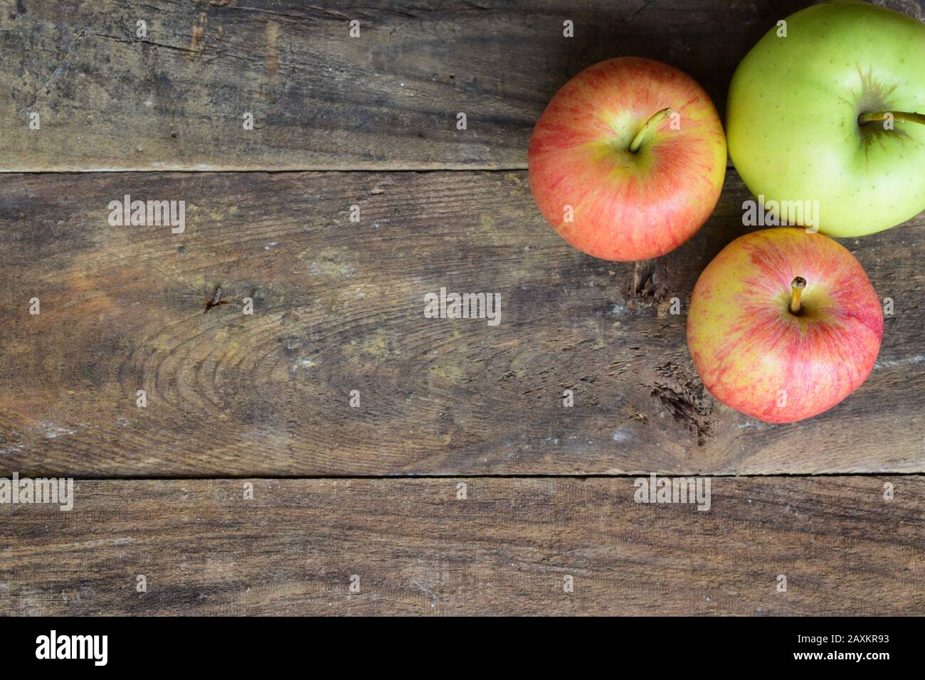 Vista verticale di due mele rosse e verdi sulla parte superiore di un vecchio tavolo in legno Foto Stock