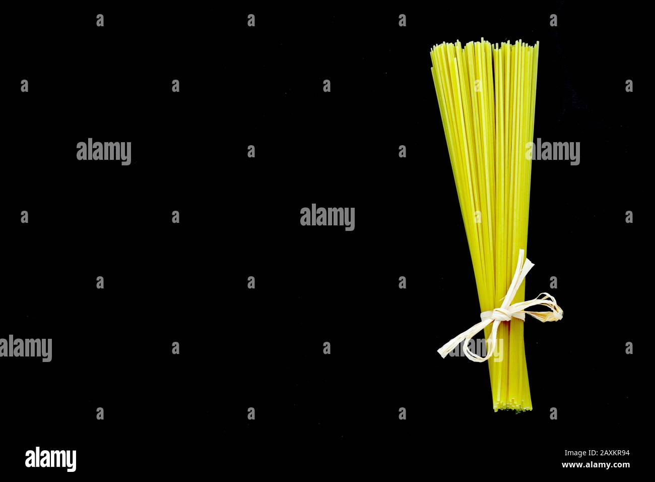 Spaghetti trecce legati insieme ad un arco con fondo completamente nero Foto Stock