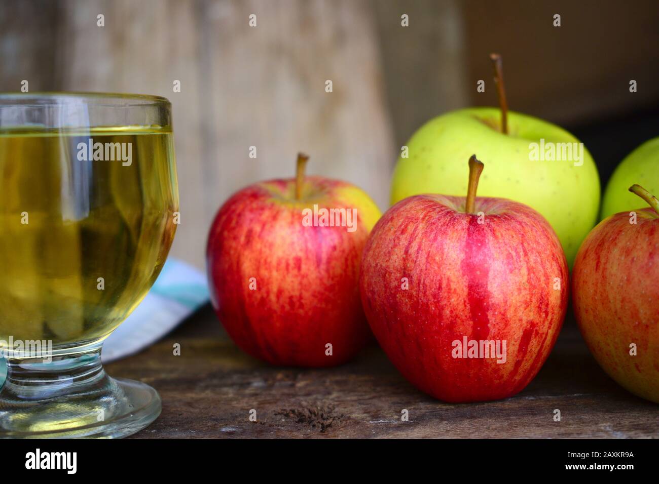 Primo piano di alcune mele e un bicchiere di succo di mela su un vecchio tavolo di legno con uno sfondo sfocato Foto Stock