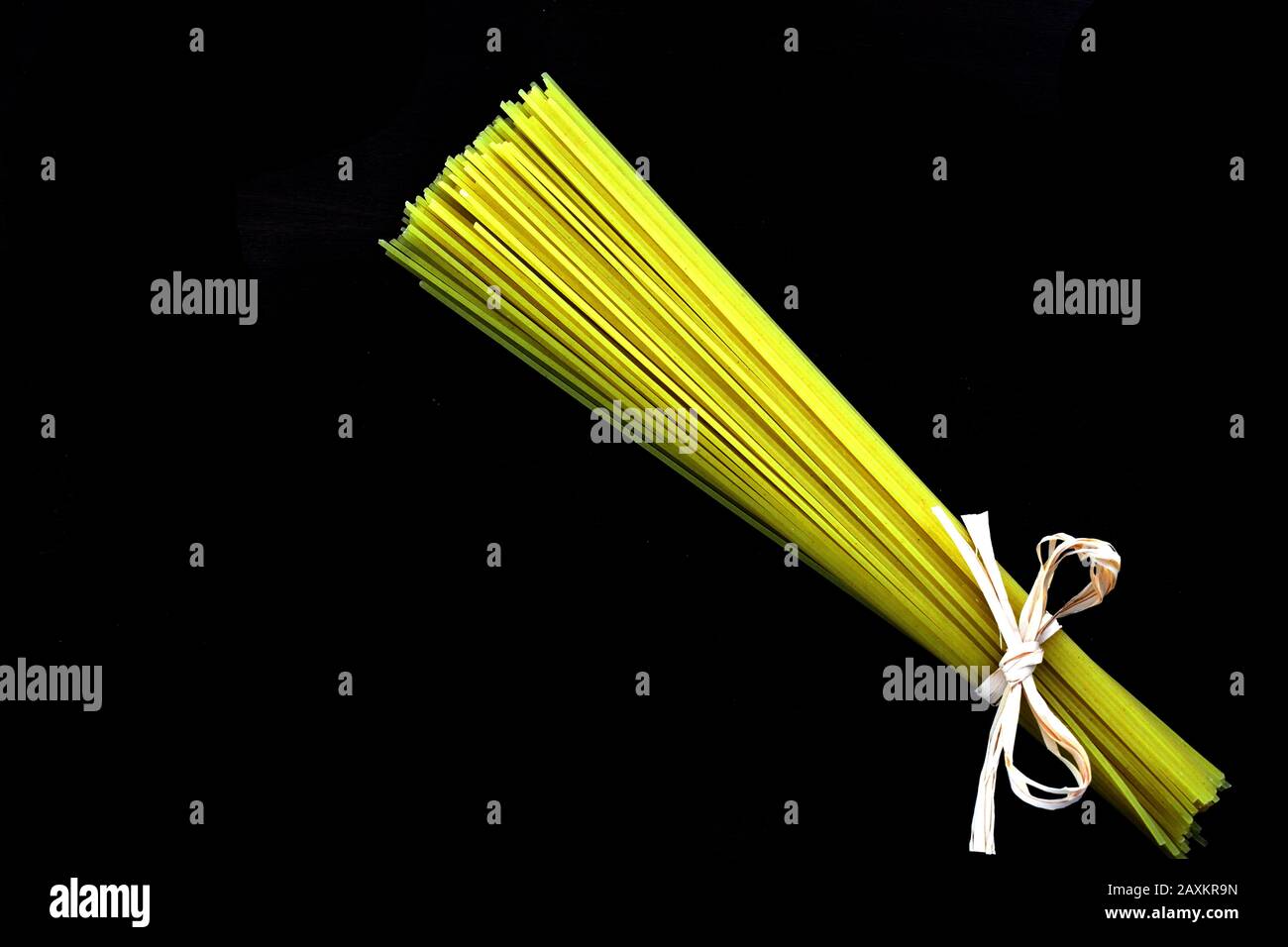 Spaghetti trecce legati insieme ad un arco con fondo completamente nero Foto Stock