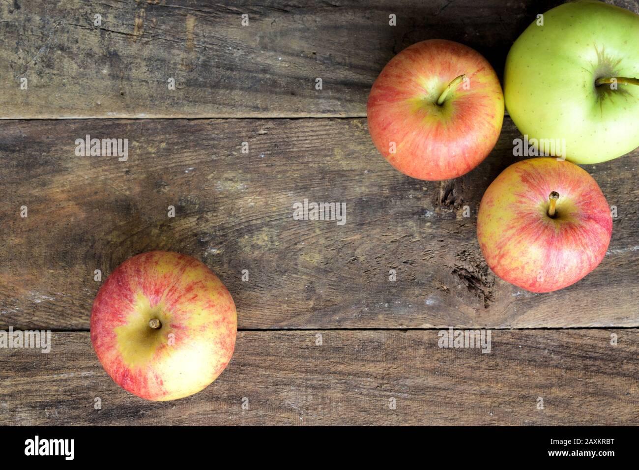 Vista dall'alto di tre mele rosse e una mela verde su un vecchio tavolo in legno Foto Stock