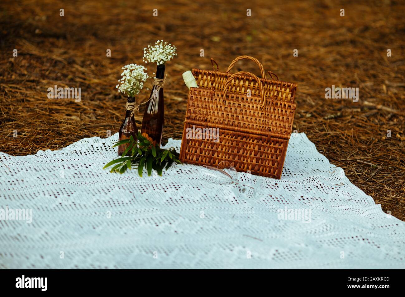 cestino da picnic in vimini nella foresta con tonalità autunnali su una coperta in pizzo vintage. Data romantica Foto Stock