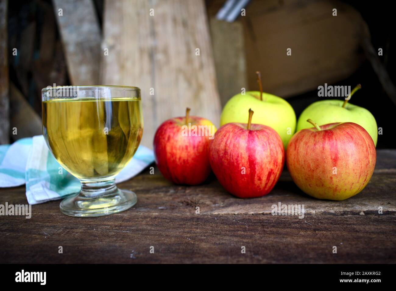 Primo piano di alcune mele e un bicchiere di succo di mela su un vecchio tavolo di legno con una schiena sfocata Foto Stock