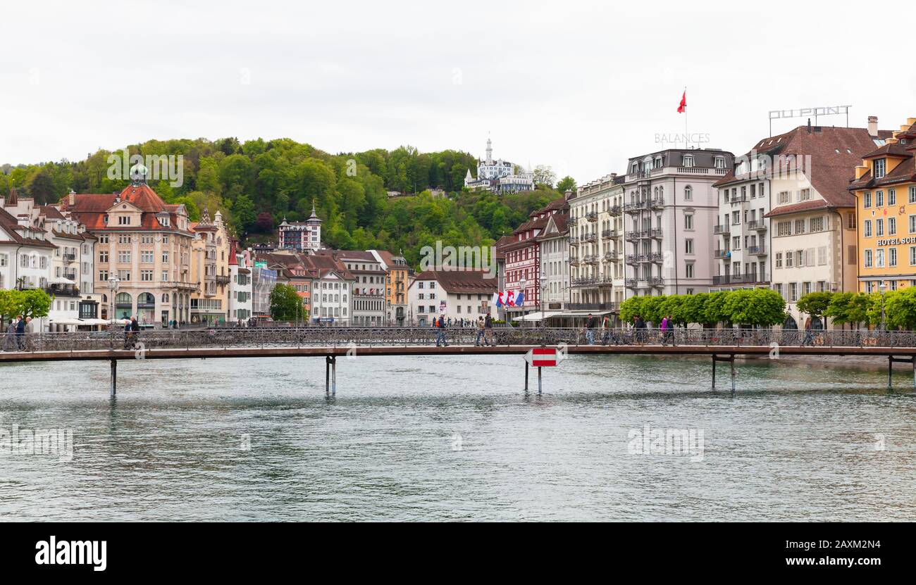 Lucerna, Svizzera - 7 maggio 2017: Vista panoramica della città di Lucerna, la gente cammina sul ponte vicino agli hotel di lusso sulla costa del fiume Reuss Foto Stock