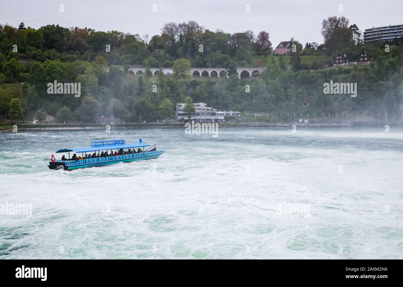 Cascate del Reno, Svizzera - 6 maggio 2017: Gita in barca alle cascate del Reno, i turisti sono in motoscafo blu sulle acque in difficoltà Foto Stock