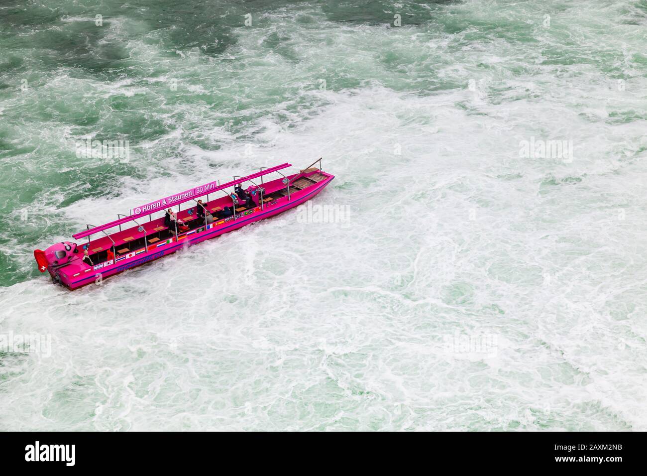 Cascate del Reno, Svizzera - 6 maggio 2017: Gita in barca alle cascate del Reno, i turisti sono in motoscafo rosa sulle acque in difficoltà Foto Stock