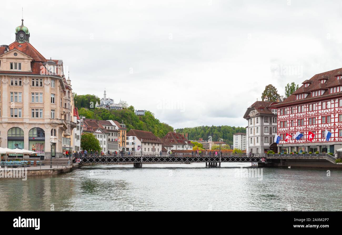 Lucerna, Svizzera - 7 maggio 2017: Paesaggio urbano di Lucerna, la gente cammina lungo il ponte vicino agli hotel di lusso sulla costa del fiume Reuss Foto Stock