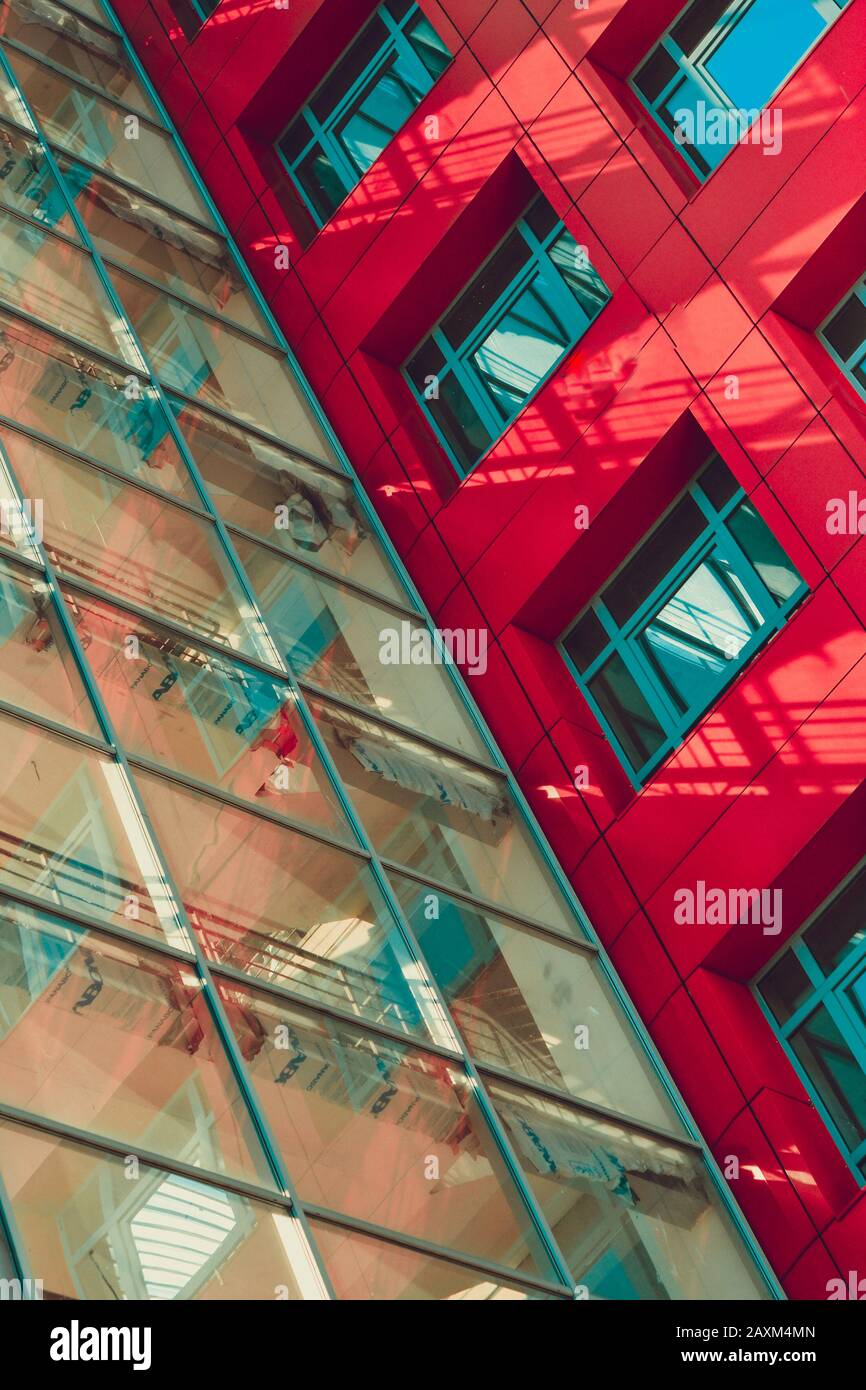 parete di vetro trasparente e un pezzo della facciata di un moderno filtro edificio rosso Foto Stock