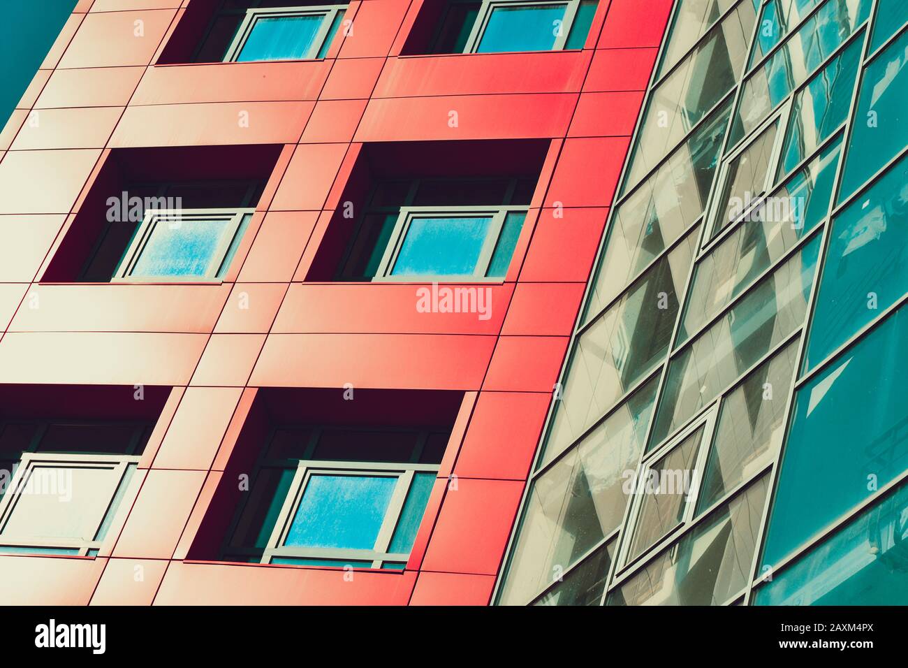 parte della facciata dell'edificio con finestre quadrate e pareti rosse e lato in vetro con filtro angolare Foto Stock