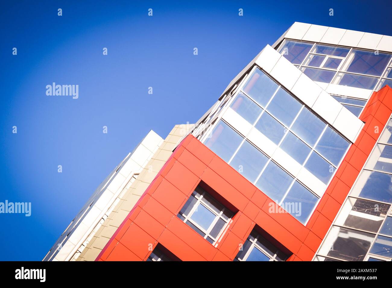 Parte della facciata della casa rossa in stile high-tech con finestre in vetro refrattivo in una giornata luminosa e soleggiata senza nuvole Foto Stock