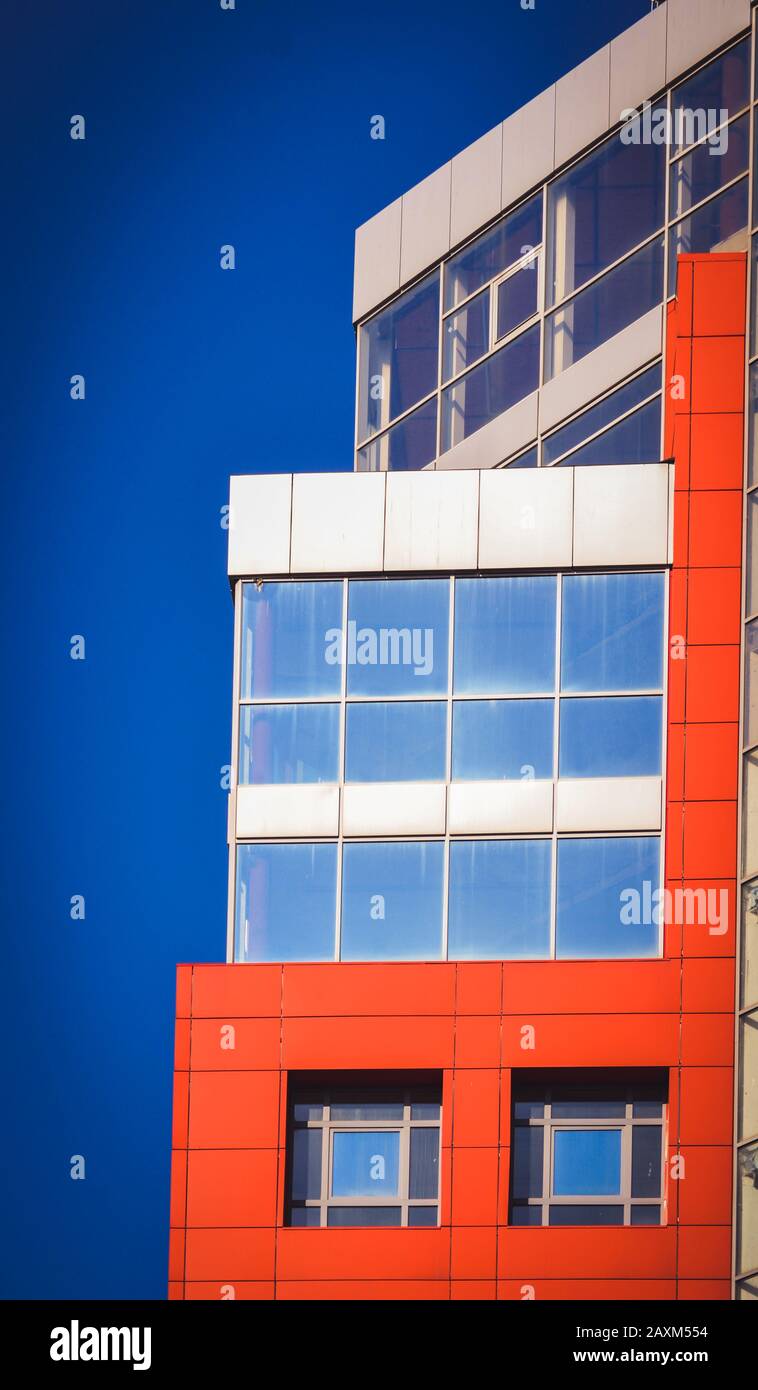Parte della facciata della casa rossa in stile high-tech con finestre in vetro refrattivo in una giornata luminosa e soleggiata senza nuvole Foto Stock