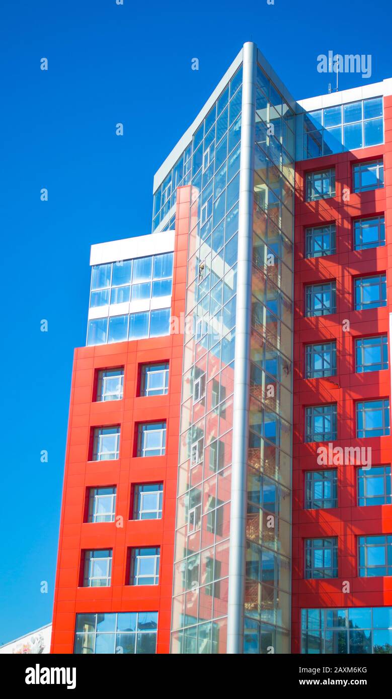 facciata di un edificio moderno nello stile di pareti rosse hi-tech, finestre quadrate in una giornata di sole con cielo blu chiaro Foto Stock