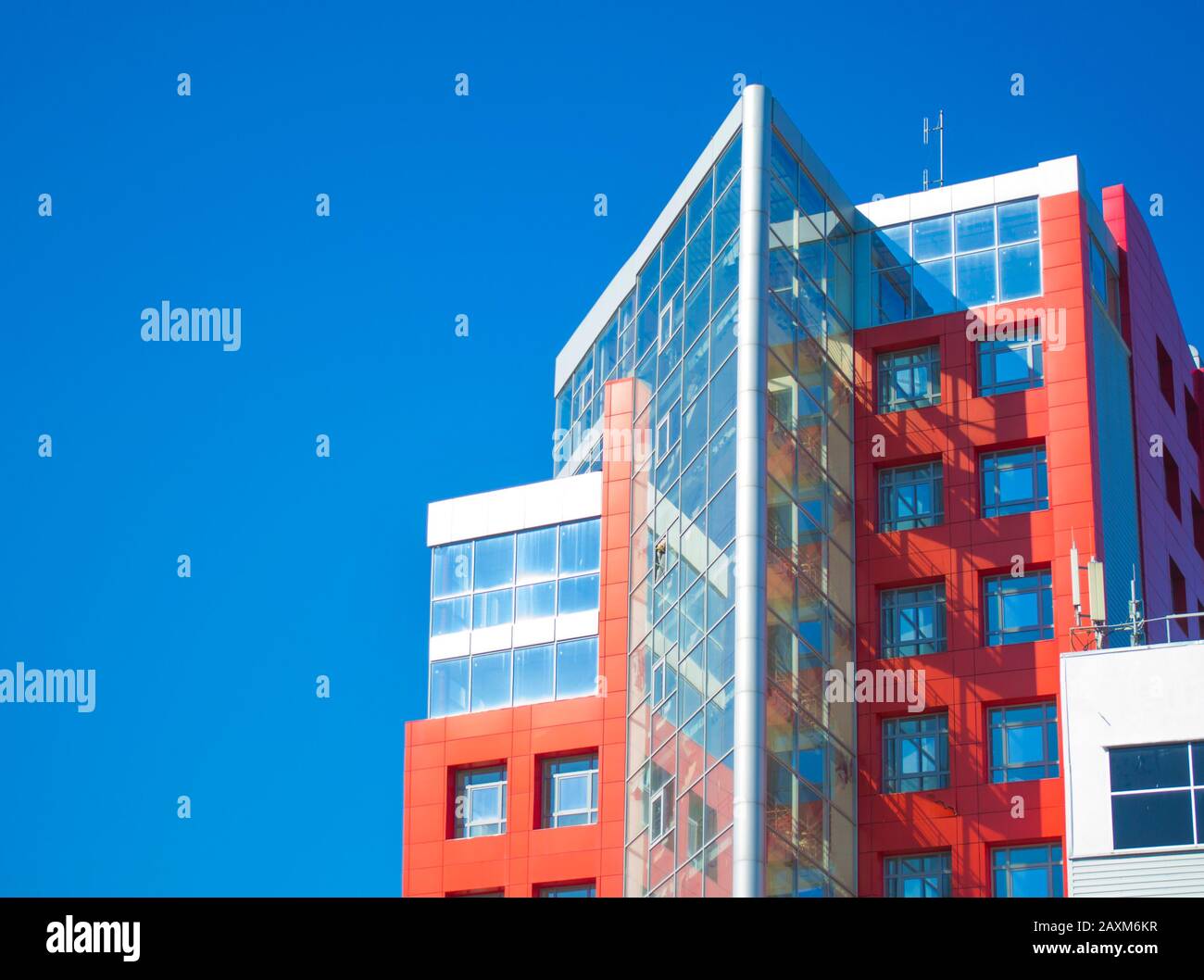 facciata di un edificio moderno nello stile di pareti rosse hi-tech, finestre quadrate in una giornata di sole con cielo blu chiaro. Spazio per il testo Foto Stock