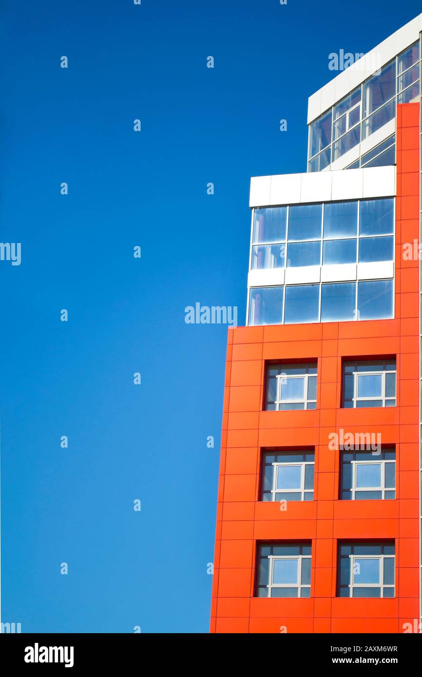 facciata di un edificio moderno nello stile di pareti rosse hi-tech, finestre quadrate in una giornata di sole con cielo blu chiaro. Spazio per il testo Foto Stock