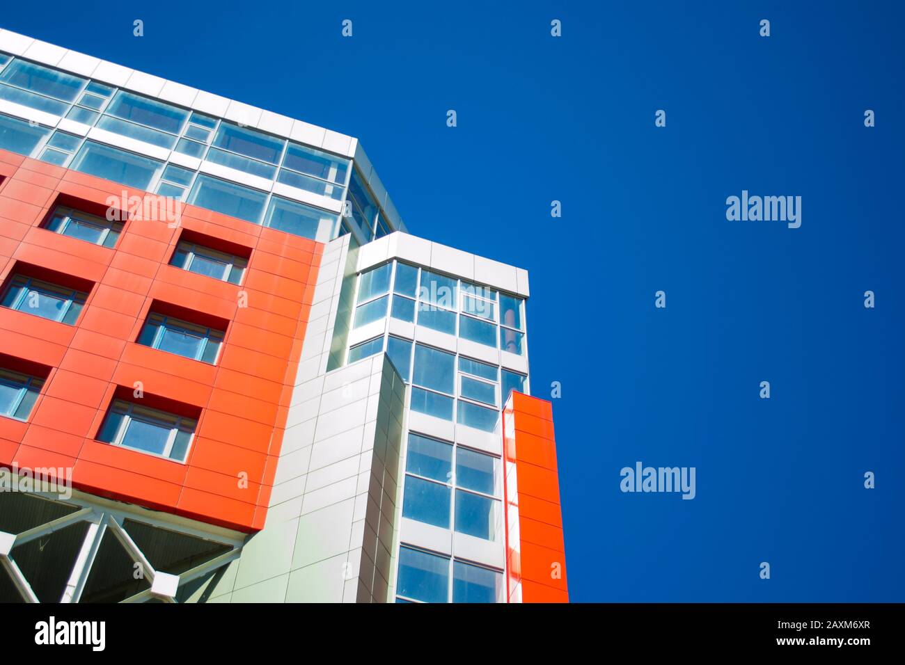 facciata di un edificio moderno nello stile di pareti rosse hi-tech, finestre quadrate in una giornata di sole con cielo blu chiaro. Spazio per il testo. Vista dal basso Foto Stock