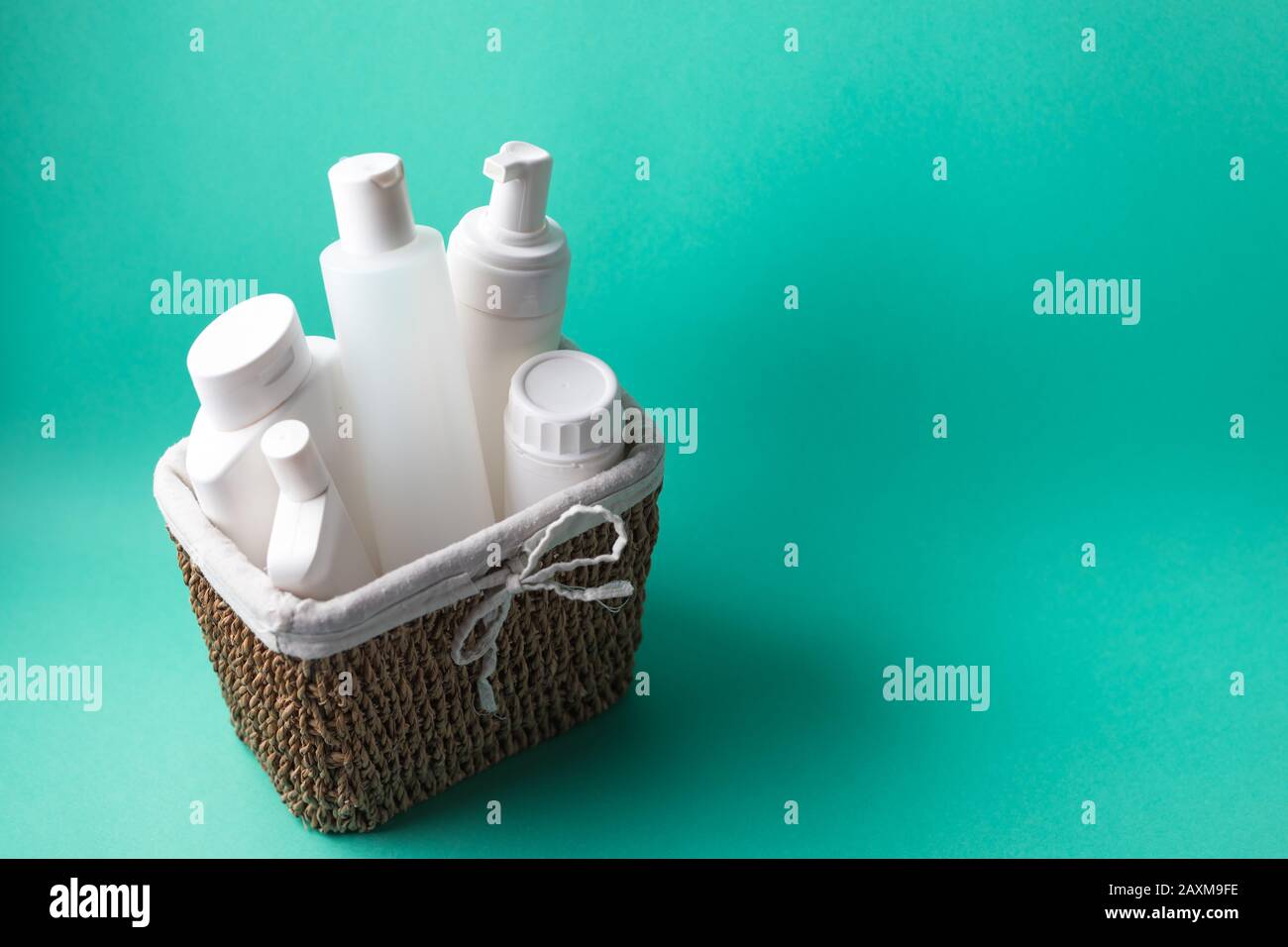 Un cestino pieno di bottiglie bianche in plastica cosmetica su sfondo blu Foto Stock