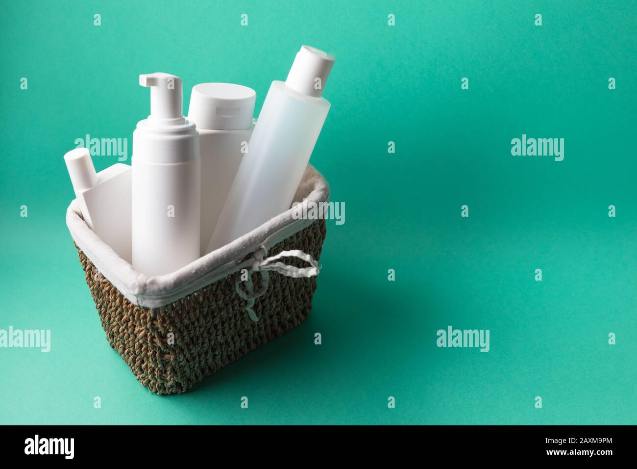 Un cestino pieno di bottiglie bianche in plastica cosmetica su sfondo blu Foto Stock