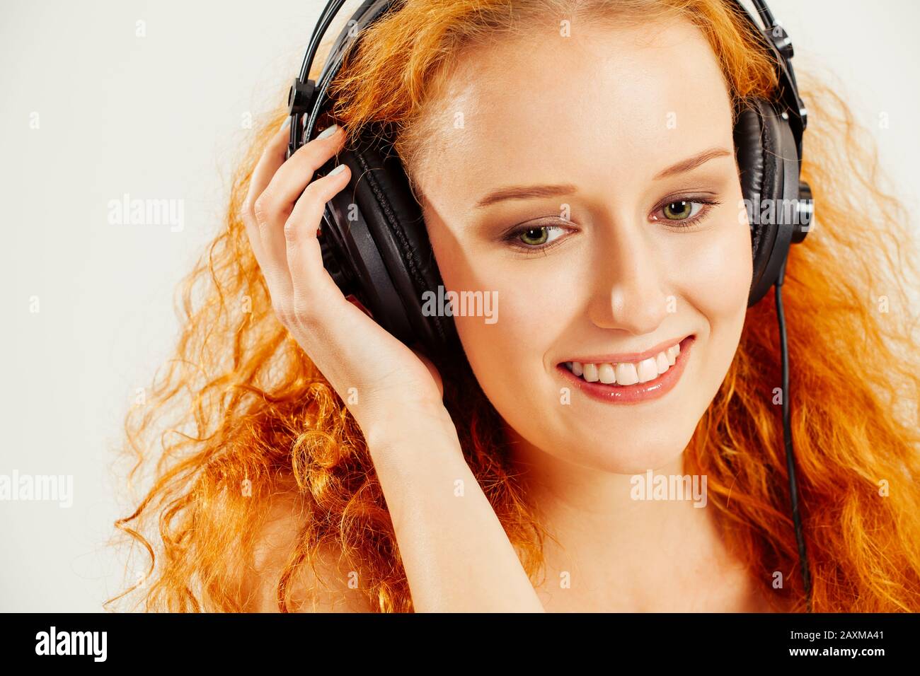 Foto di un bel giovane redhead ascoltando le cuffie e sorridendo. Foto Stock