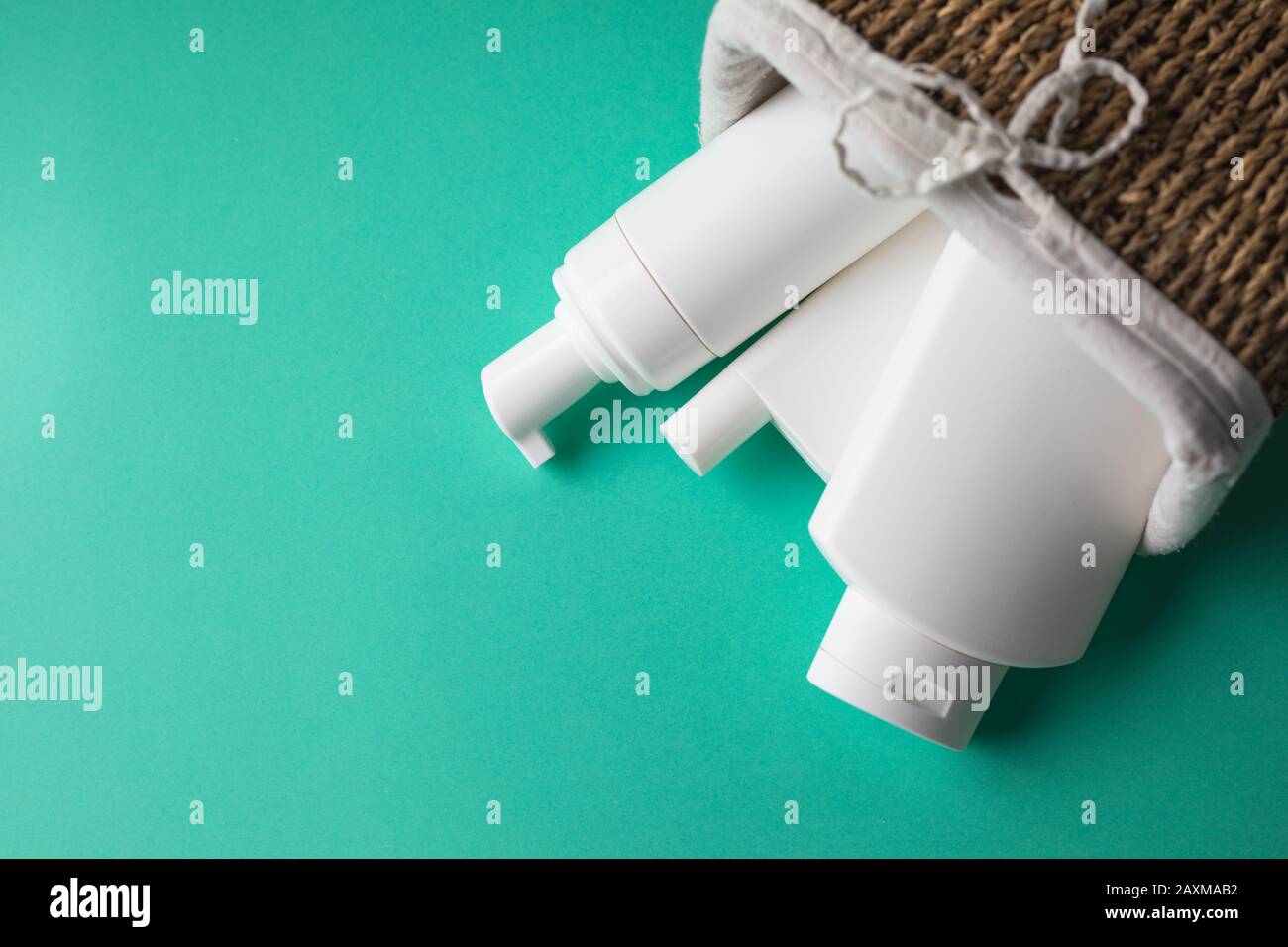 Un cestino pieno di bottiglie bianche in plastica cosmetica su sfondo blu Foto Stock