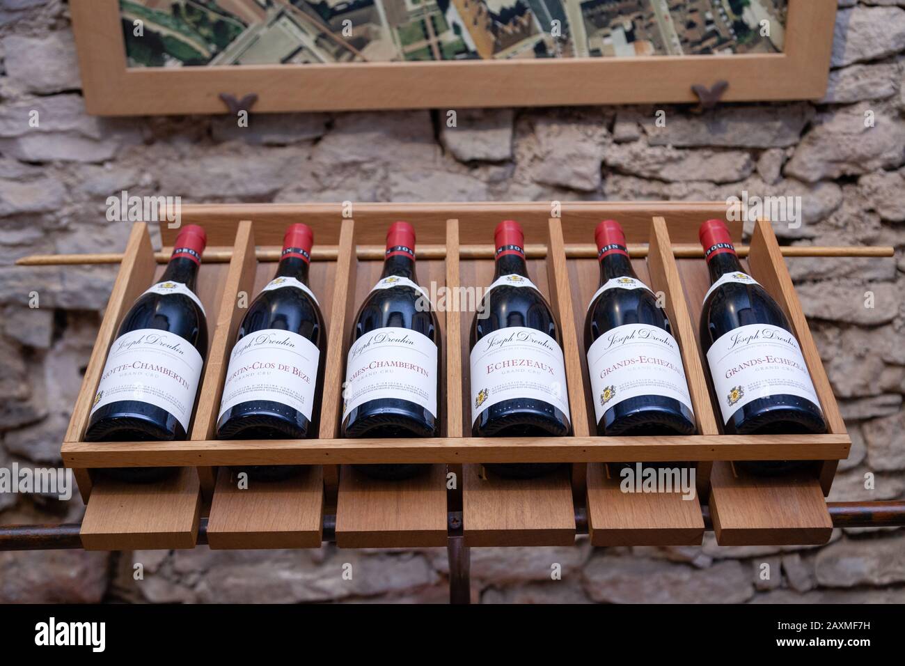 Francia Borgogna 2019-06-19. Bottiglie di vino in linea su un rack di legno, famosi vini rossi Pinot Nero in negozio presso la cantina Joseph Drouhin. Concept pr vino francese Foto Stock