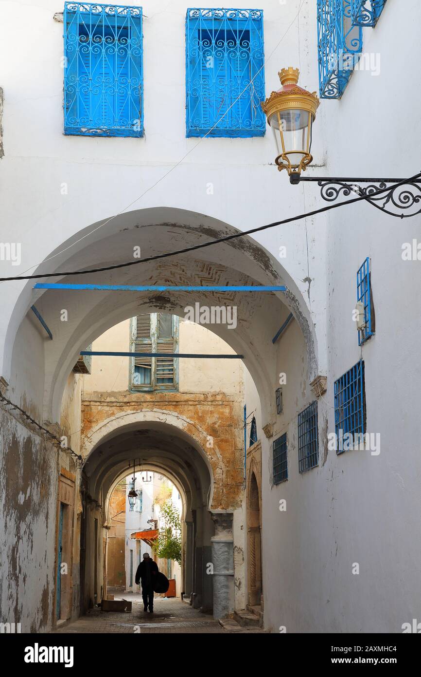 Tipica strada acciottolata e stretta con colonne e portici all'interno della storica medina di Tunisi, Tunisia Foto Stock