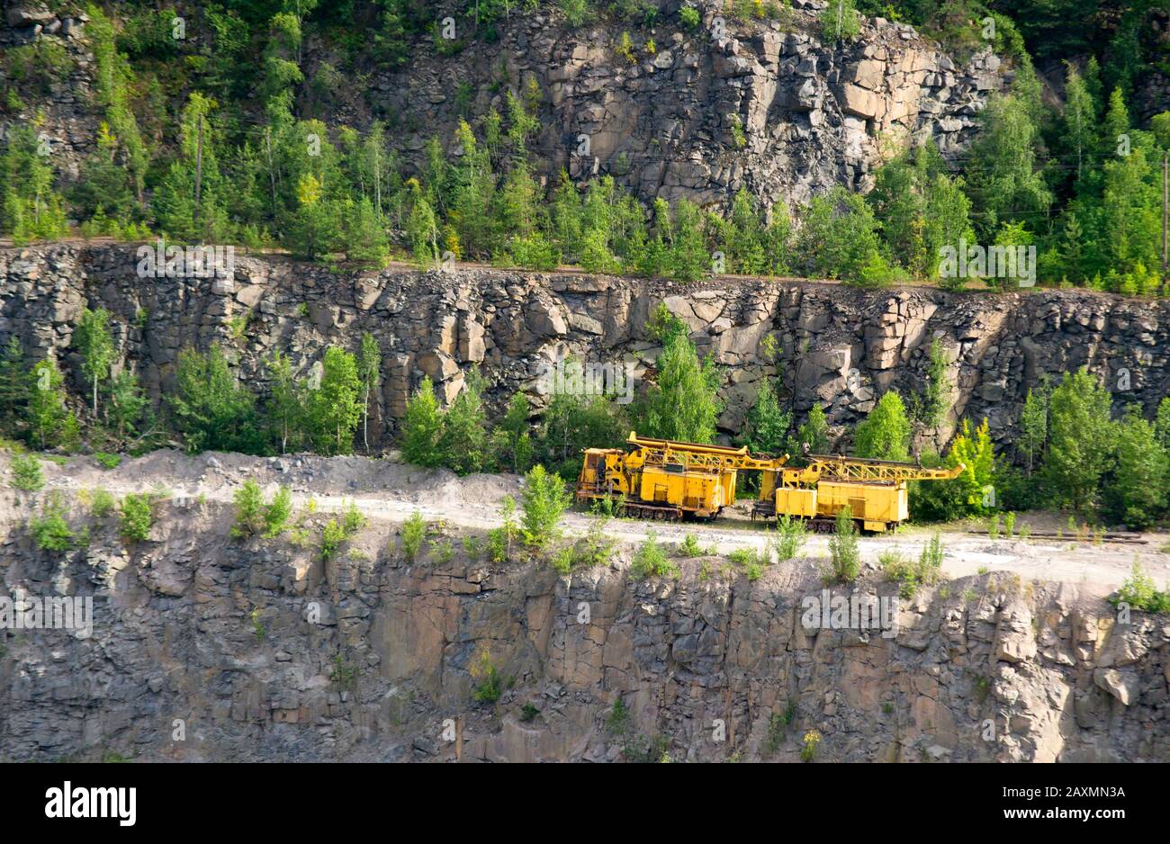 macchine gialle per l'estrazione del granito in piedi su strada su una roccia nella cava per il granito Foto Stock