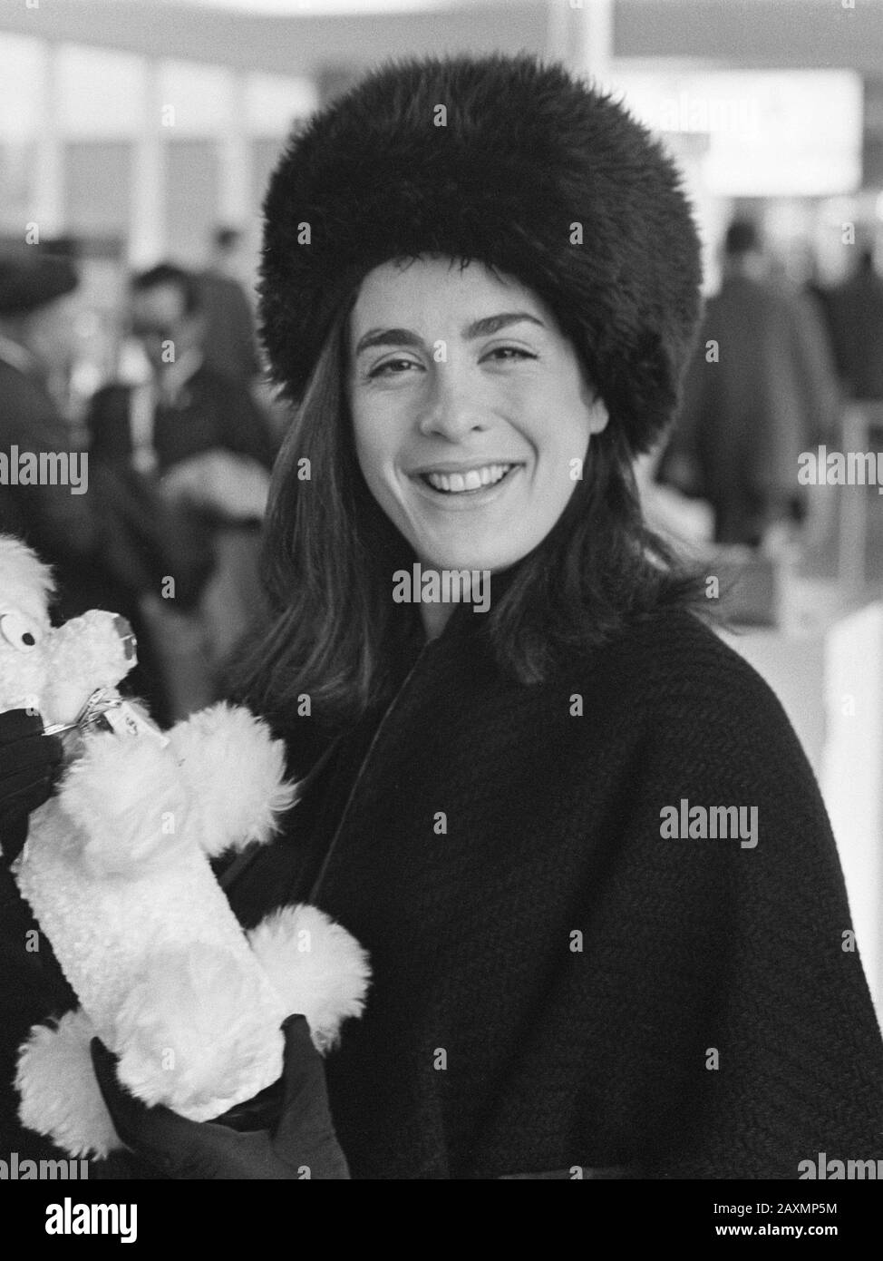 Aankomst Eleanor Bron en Dudley Moore op Schiphol 31 januari 1968 Arrivo all'aeroporto di Amsterdam Schiphol. Attrice Eleanor Bron, sorridente alla macchina fotografica, indossando un cappello di pelliccia nera e shawl lavorato a maglia e tenendo un giocattolo farcito che assomiglia ad un poodle stilizzato. Foto Stock