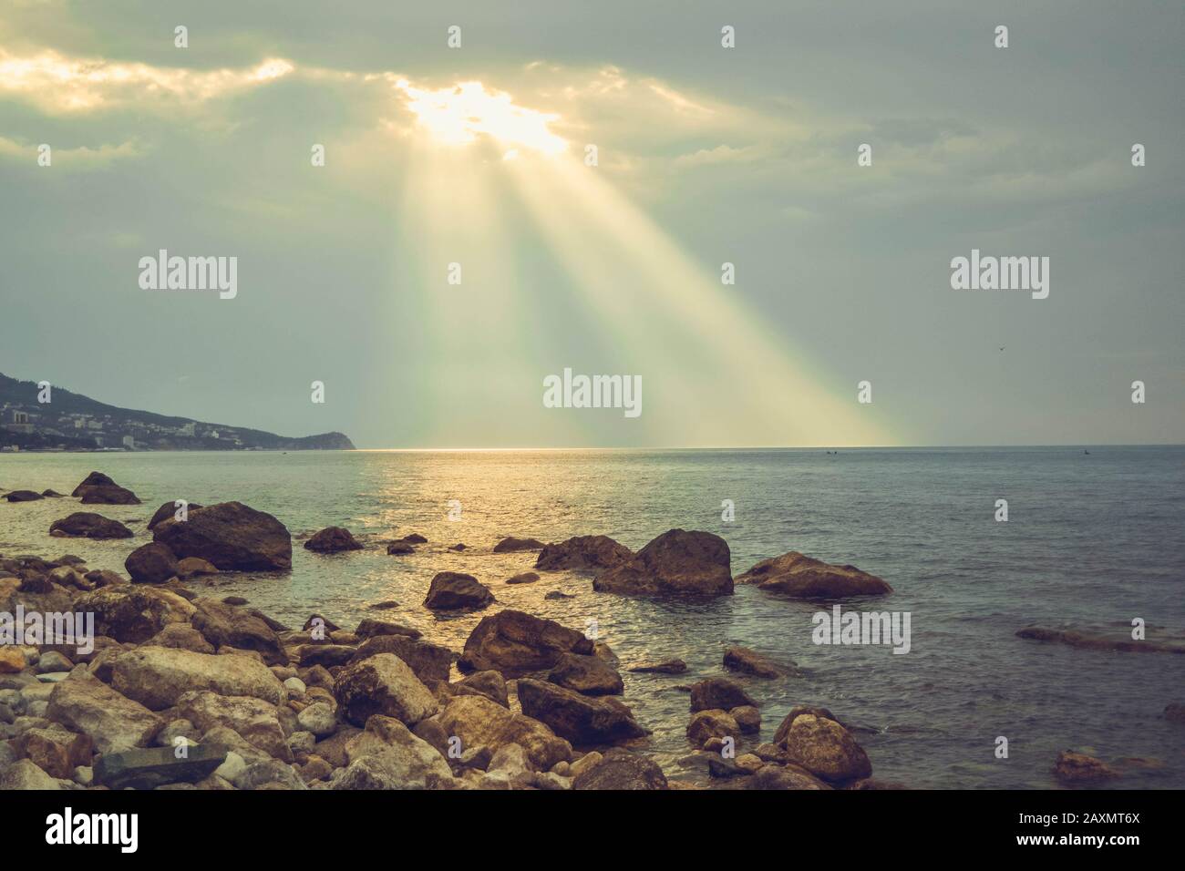 i raggi del sole splendono sul mare e sulla costa rocciosa Foto Stock