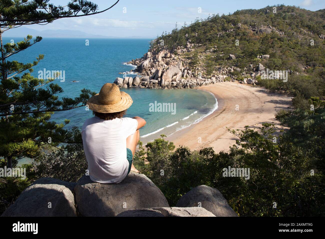 Capelli ricci con cappello e costume da bagno, sulla roccia, ammirando la baia Foto Stock