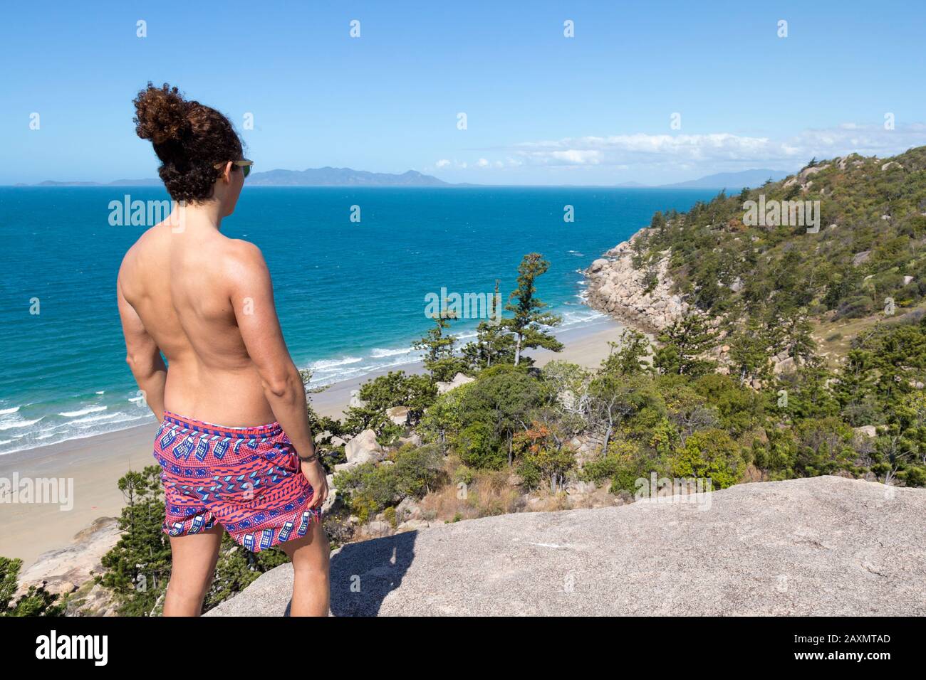 Giovane uomo con un boccale e costume da bagno, con vista sull'oceano Foto Stock