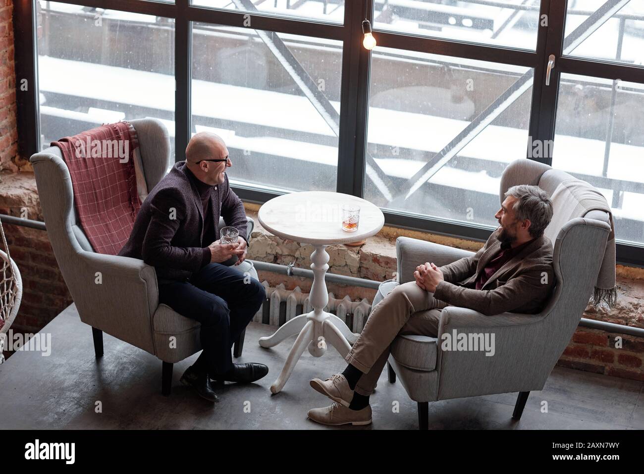 Sopra la vista di positivi ricchi uomini di mezza età chiacchierando e bevendo whisky in un lussuoso pub Foto Stock