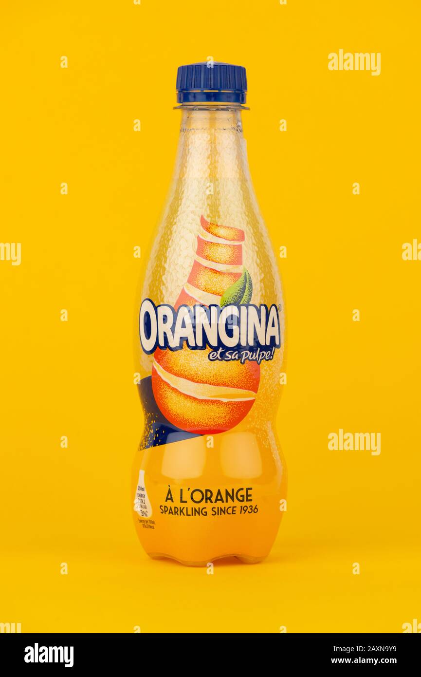 Una bottiglia di Orangina sparata su sfondo giallo. Foto Stock