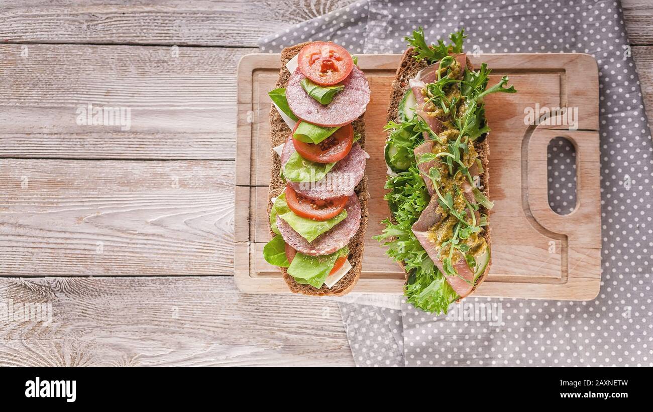 Colazione mediterranea o pranzo. Bruschetta con carne di prosciutto affumicato e bruschetta con salame e pomodori, formaggio cremoso, pea microgreens e pe Foto Stock