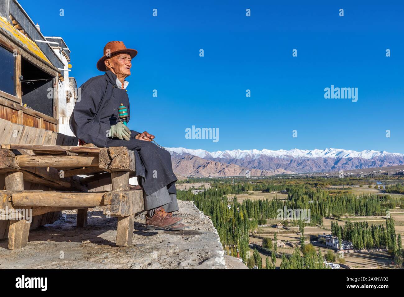 Uomo anziano con una preghiera ruota in appoggio in corrispondenza di Spituk Gompa, Leh district, Ladakh, India Foto Stock
