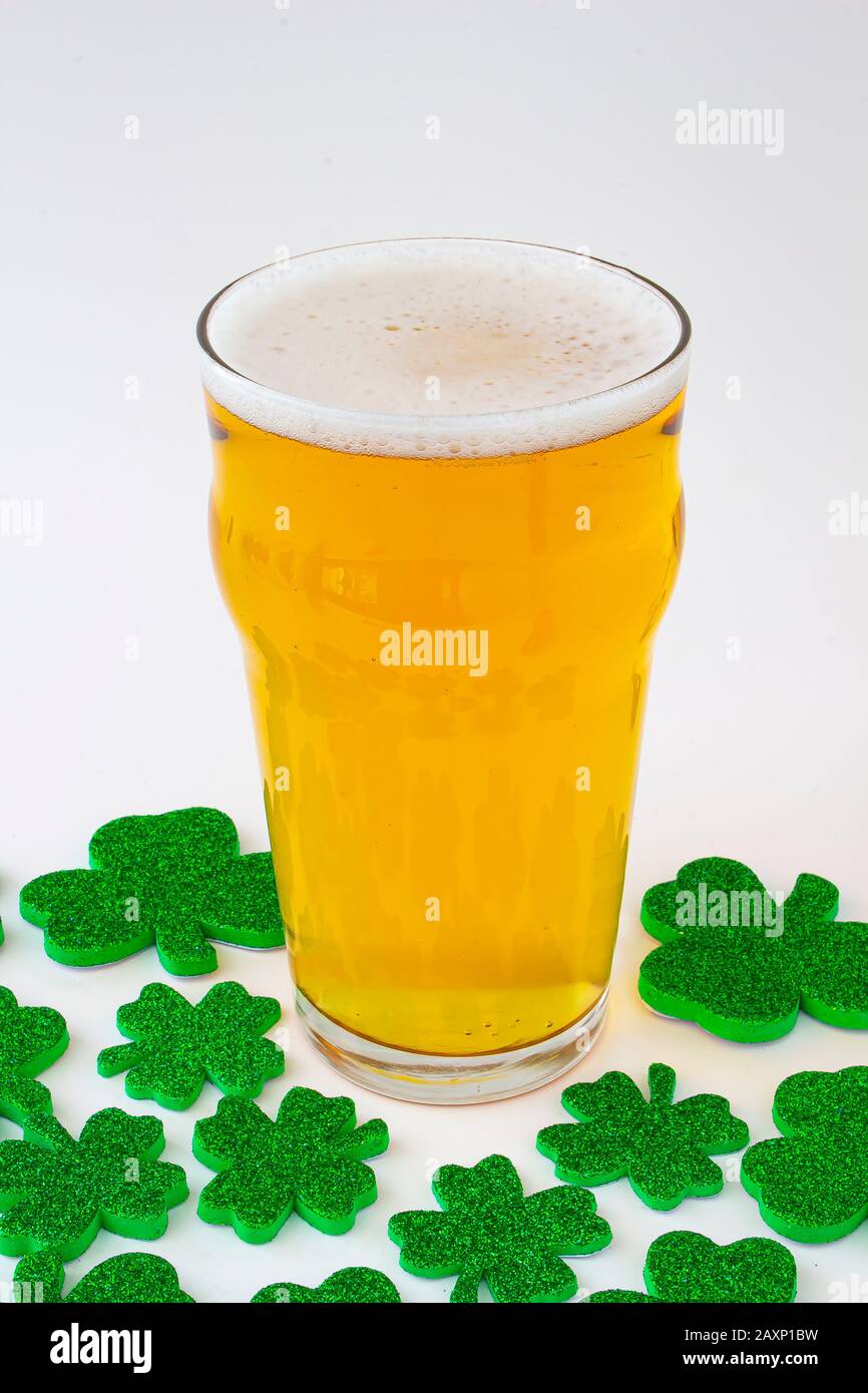 Una Pinta di birra con i verdi trifogli intorno Foto Stock
