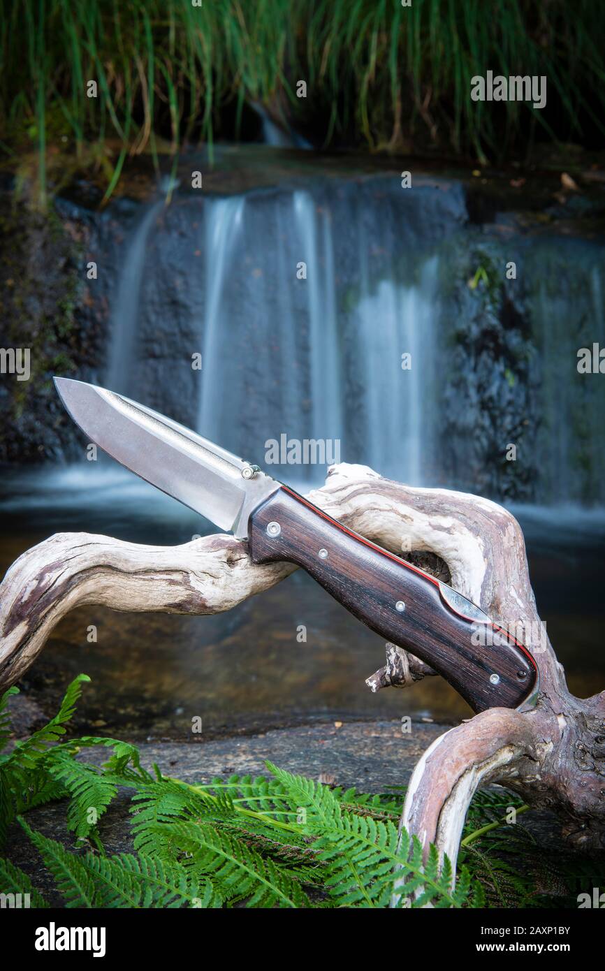 coltello per il bushcraft e la sopravvivenza nella natura selvaggia vicino ad una cascata Foto Stock