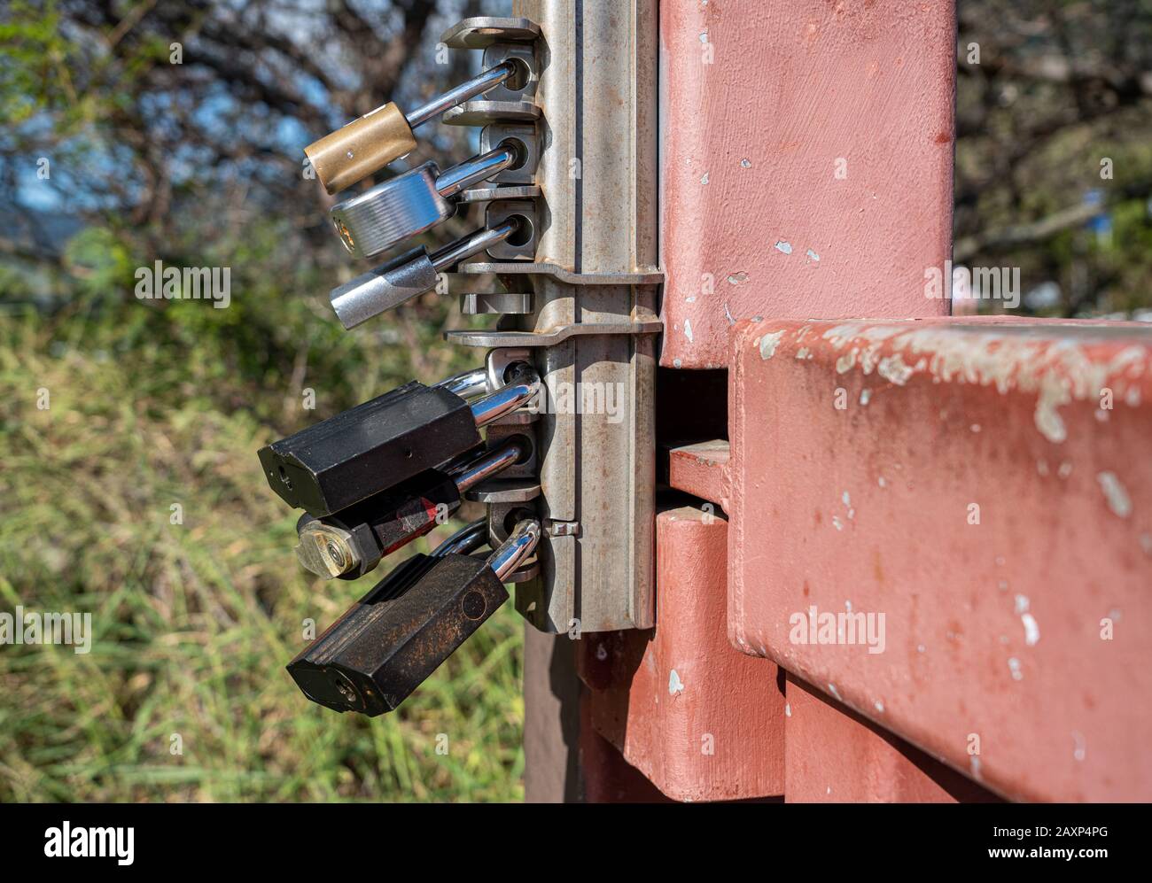 Overkill con sei lucchetti diversi che bloccano l'apertura di un cancello metallico Foto Stock
